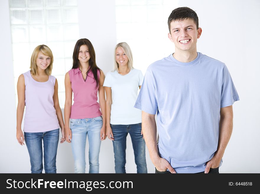 Four smiling friends standing and looking at camera. Focused on the boy who standing in front. Front view. Four smiling friends standing and looking at camera. Focused on the boy who standing in front. Front view.