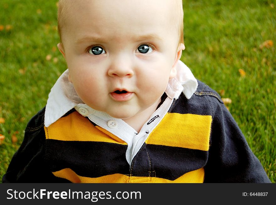 Cute baby boy looking thoughtful on the grass. Cute baby boy looking thoughtful on the grass