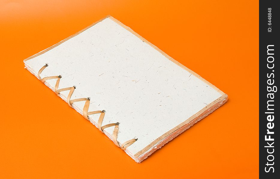 Recycled notepad over an orange background