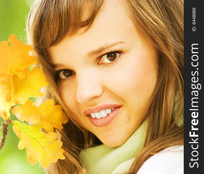 Beautiful romantic brunette with golden autumn leaf close-up portrait