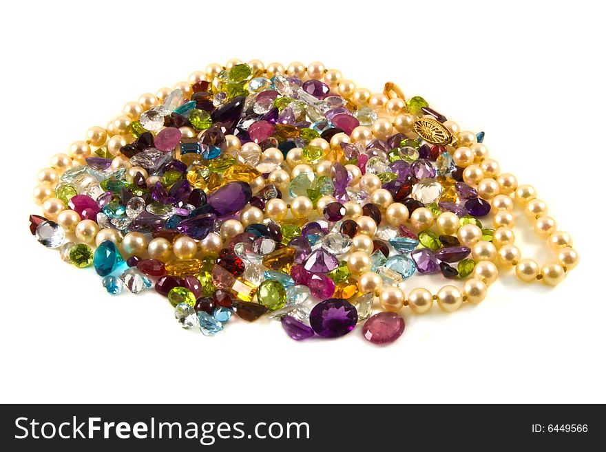 A large group of mixed faceted gemstones with pearls on a white background