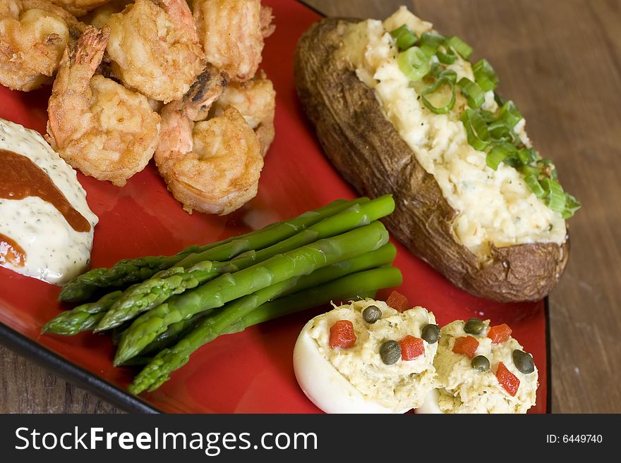 Plate of shrimp, asparagus, deviled eggs, and baked potato. Plate of shrimp, asparagus, deviled eggs, and baked potato