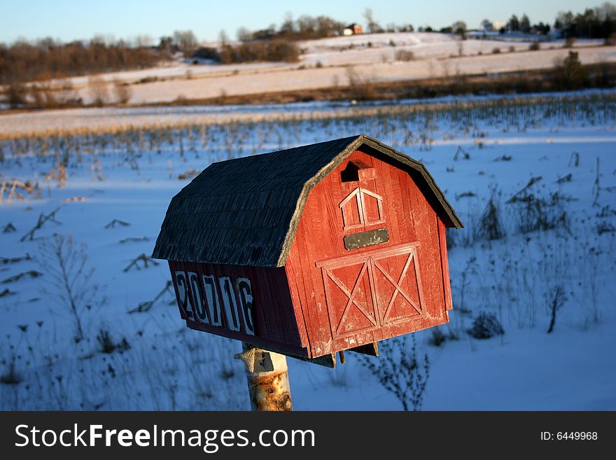 Red barn mailbox on farmland and fields.