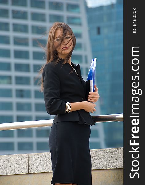 Business woman with documents outside a modern office building