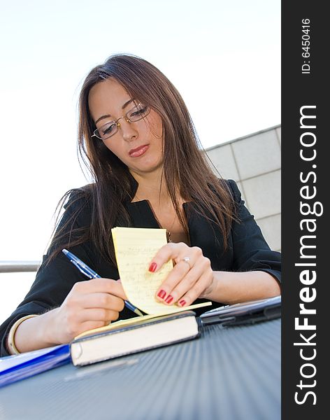 Business woman writes notes in open-air cafe in downtown