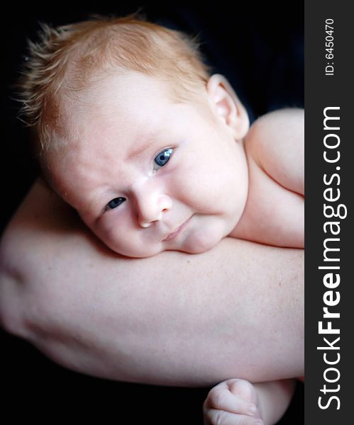 A baby is laying down in a studio on his mother's arm.  Vertically framed shot. A baby is laying down in a studio on his mother's arm.  Vertically framed shot.