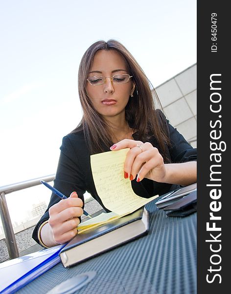 Business woman writes notes in open-air cafe in downtown