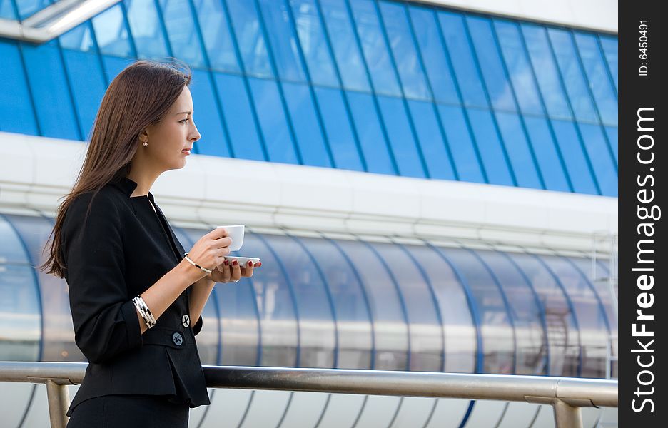 Business woman drinks a coffee outdoors in modern downtown. Business woman drinks a coffee outdoors in modern downtown