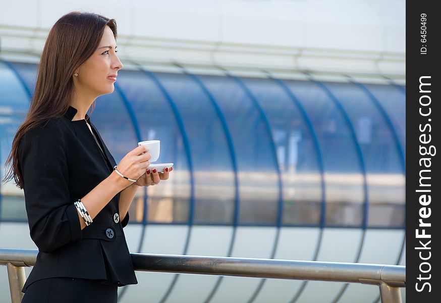 Business woman drinks a coffee outdoors in modern downtown. Business woman drinks a coffee outdoors in modern downtown