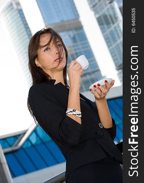 Business woman drinks a coffee outdoors in modern downtown. Business woman drinks a coffee outdoors in modern downtown