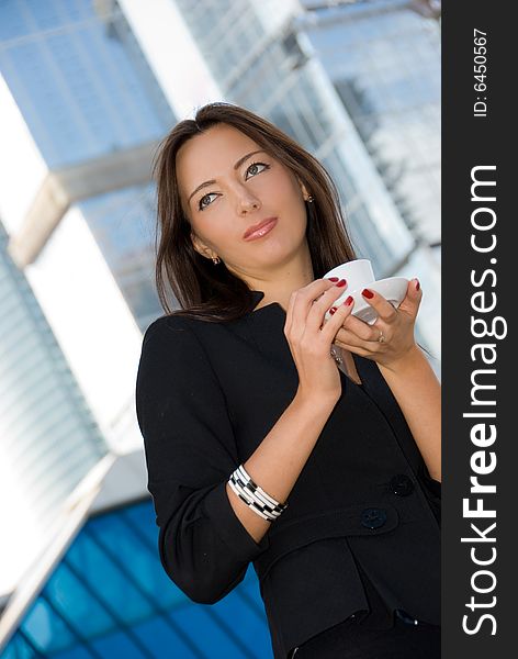 Business woman drinks a coffee outdoors in modern downtown. Business woman drinks a coffee outdoors in modern downtown