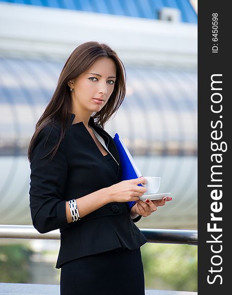 Business woman drinks a coffee outdoors in modern downtown. Business woman drinks a coffee outdoors in modern downtown