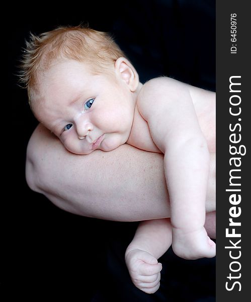 A baby is laying down in a studio on his mother's arm.  Vertically framed shot. A baby is laying down in a studio on his mother's arm.  Vertically framed shot.