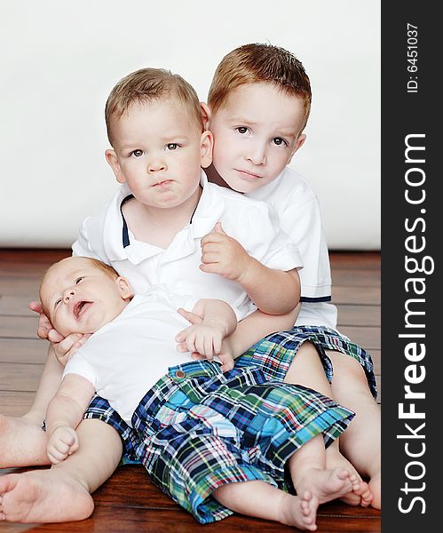 Photo of three young children posing on the floor for the camera. Vertically framed photo. Photo of three young children posing on the floor for the camera. Vertically framed photo.