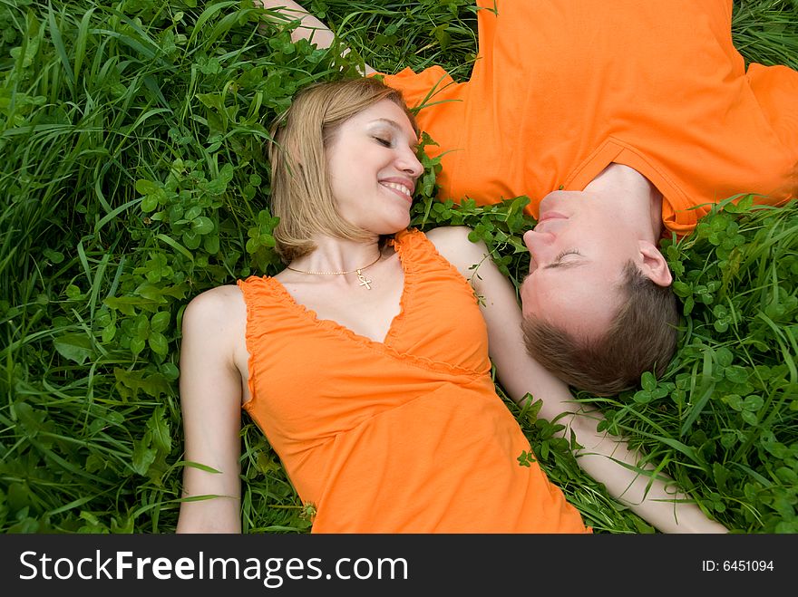 Loving couple lies side by side on the grass