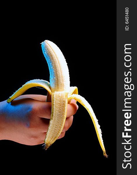 Hand holding a banana over black background