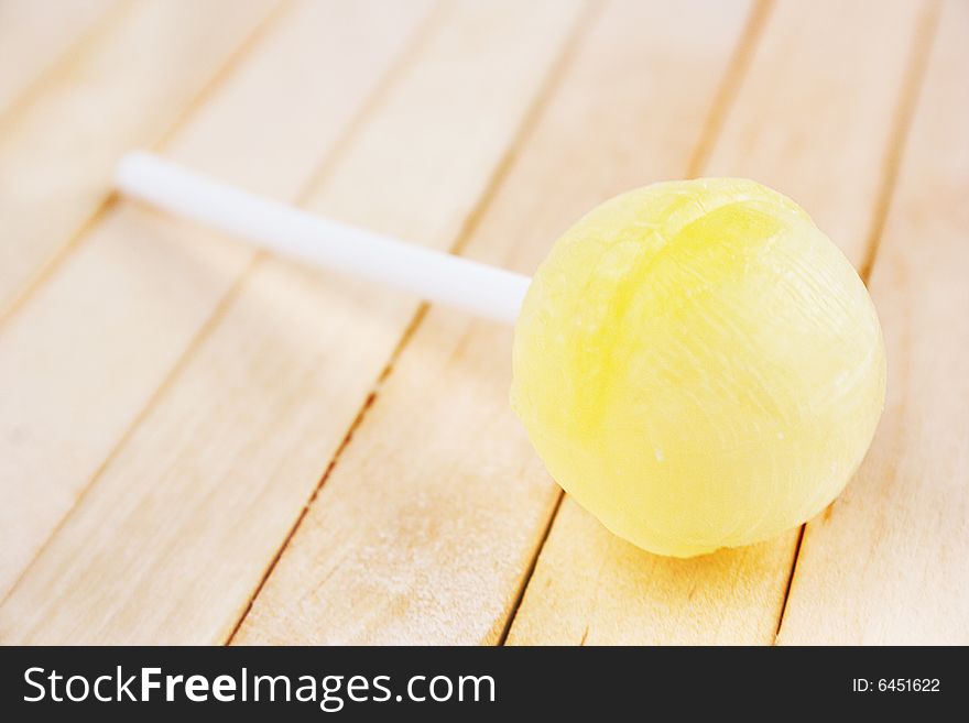 Yellow lollipop on the wooden background