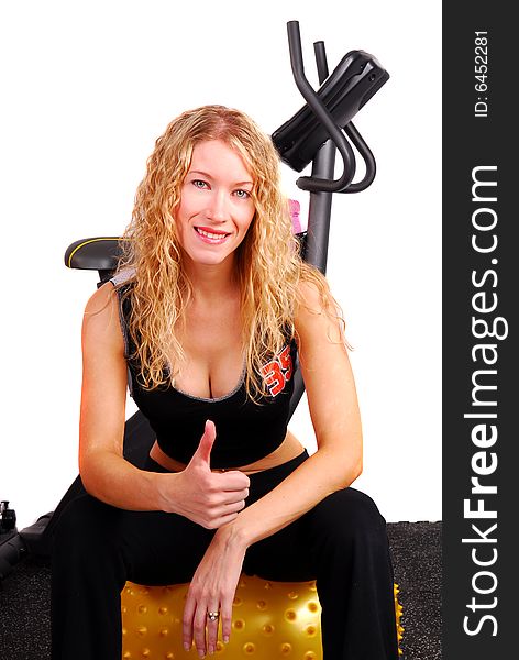 Attractive young woman sitting on an exercise ball giving the thumbs up sign. Attractive young woman sitting on an exercise ball giving the thumbs up sign