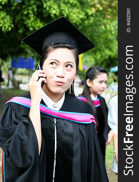 Asian university graduate talking on her cell phone.