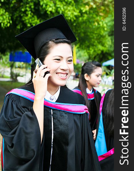 Asian university graduate talking on her cell phone.