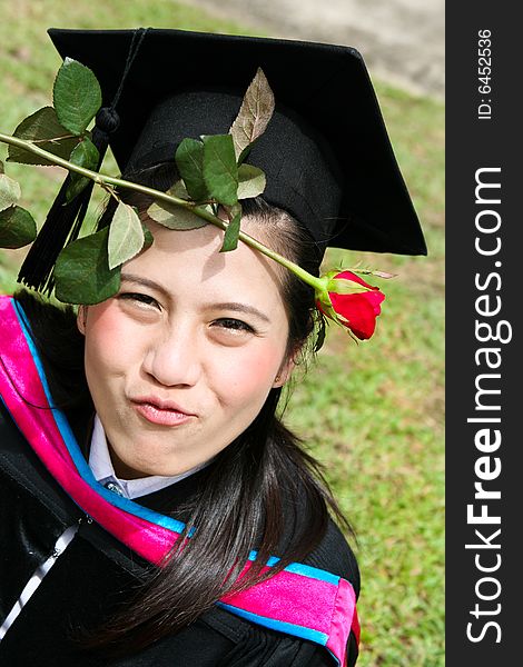 Beautiful Asian university graduate with a red rose.