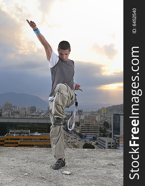 Young break dancer dancing on top of the building with blured cityscape and sunset in background. Young break dancer dancing on top of the building with blured cityscape and sunset in background