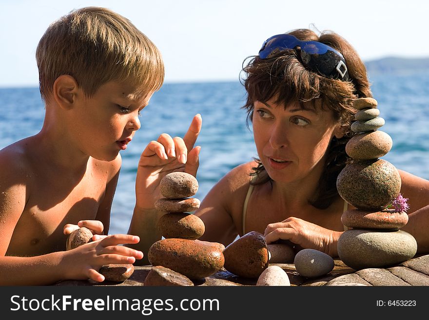 Mom with the son builds pyramids from the stones on the beach. Mom with the son builds pyramids from the stones on the beach