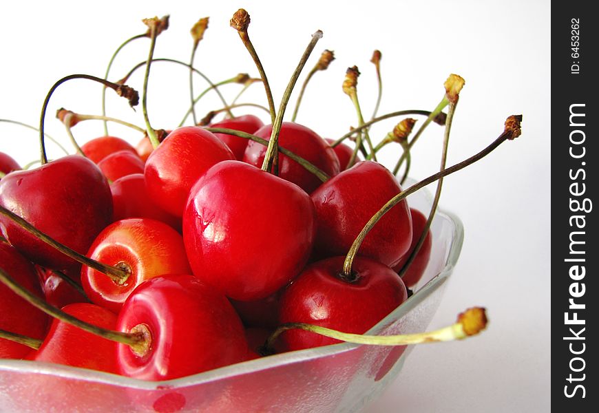 Tasty cherries in glass bowl isolated on white background