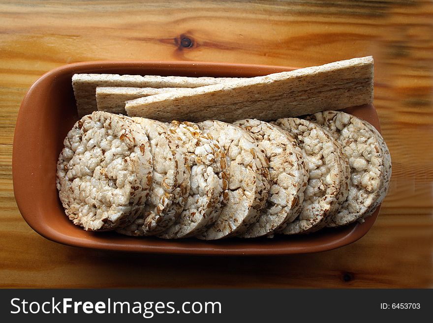 Crackers in brown bowl on wooden table. Crackers in brown bowl on wooden table