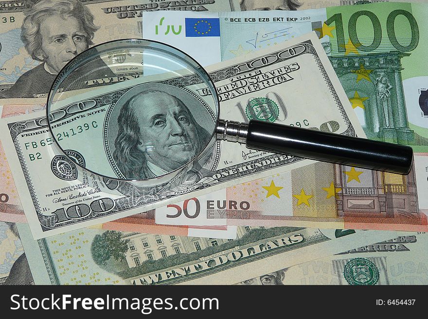 Notes of dollar and euro under magnifying glass