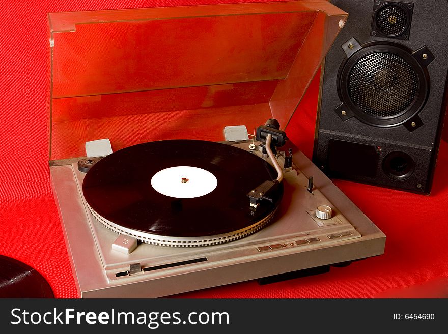 Record player with records and speaker on red ground