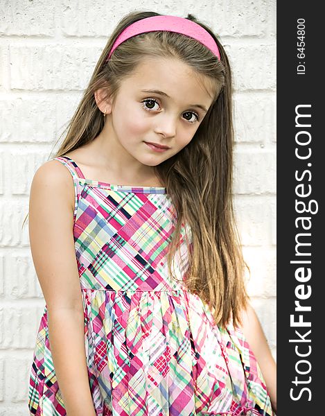 Beautiful portrait of a young girl dressed in plaid with a pink headband. Beautiful portrait of a young girl dressed in plaid with a pink headband.