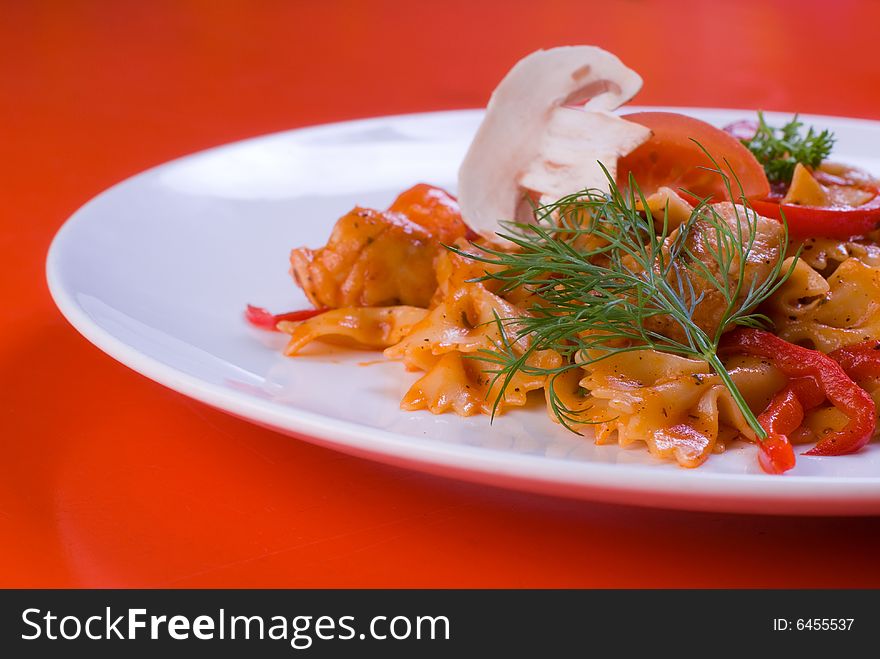 Freshly cooked plate of macaroni with chamignons and tomatoes sprinkled with fresh green herbs.