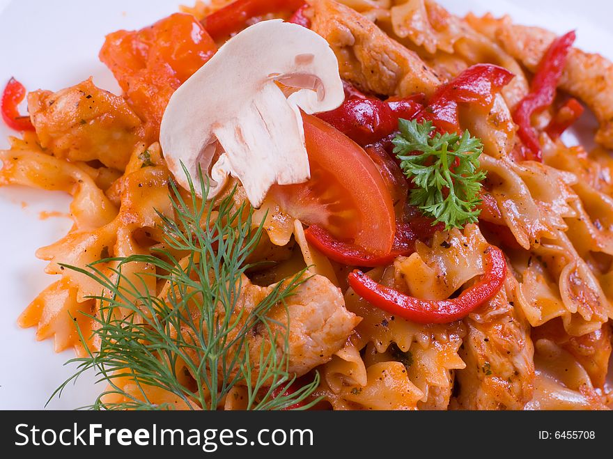 Freshly cooked plate of macaroni with chamignons and tomatoes sprinkled with fresh green herbs.