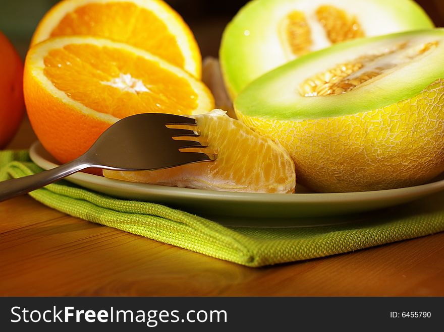 Fresh oranges and melon on the table in the kitchen