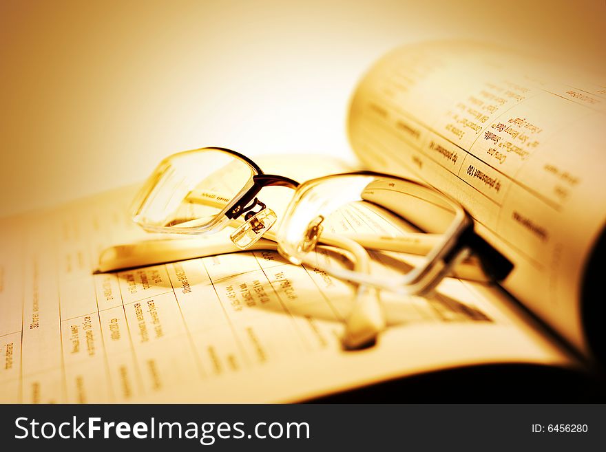 Book and Glasses on yellow background