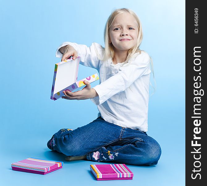 Young girl with unpleasant gift over blue background. Young girl with unpleasant gift over blue background