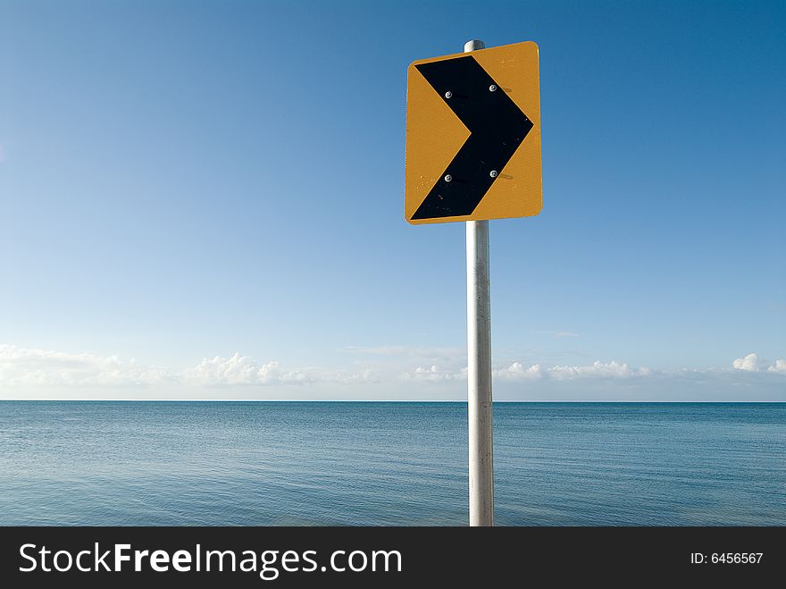 Direction sign in front of calm sea and cloudless sky. Direction sign in front of calm sea and cloudless sky
