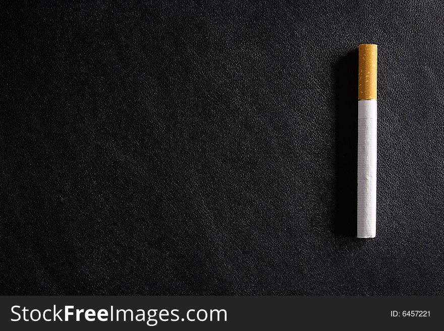 Cigarette tobacco on the black leather background. Cigarette tobacco on the black leather background