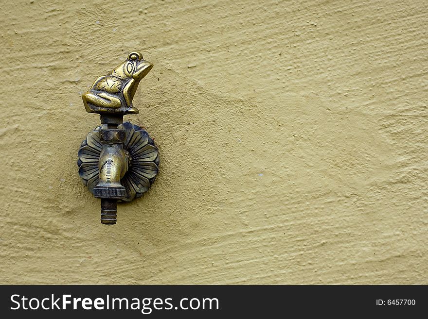 Old bronze faucet with frog form on wall. Old bronze faucet with frog form on wall