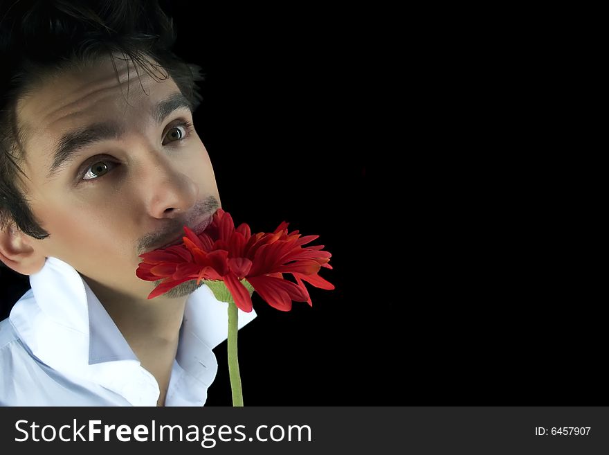 Young man with a red flower isolated on a black background