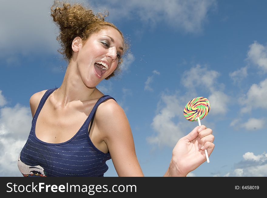 Fun blonde girl with lollypop in clouds background
