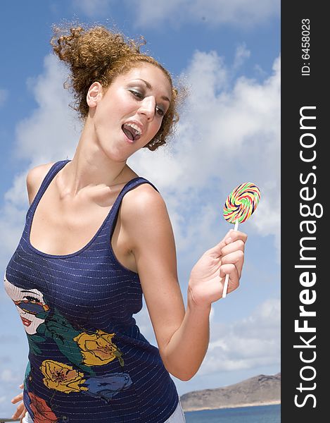 Fun blonde girl with lollypop in clouds background