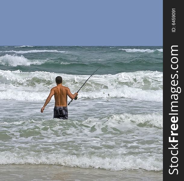 Man surf fishing in the rough surf.