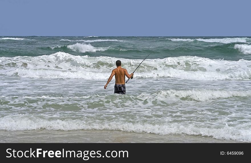 Man surf fishing in the rough surf.