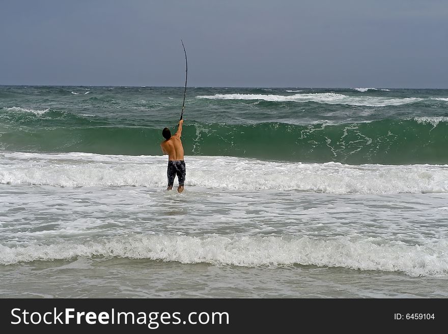 Man surf fishing, casting into the ruff ocean.