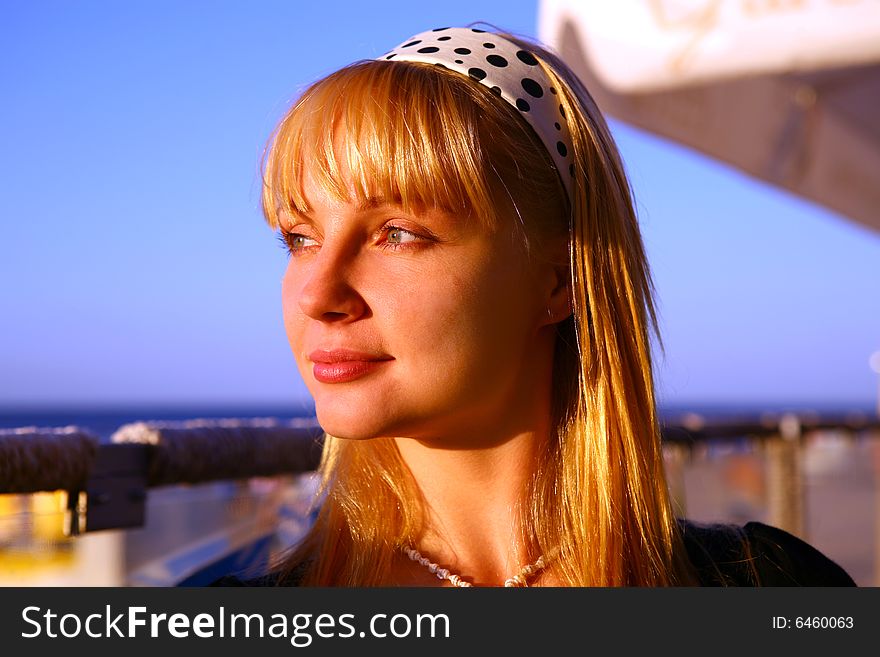 Beautiful blond girl look at sunset from summer kafe on the beach. Beautiful blond girl look at sunset from summer kafe on the beach