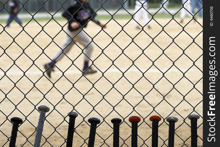 Baseball bats learning against dugout fence as game is played