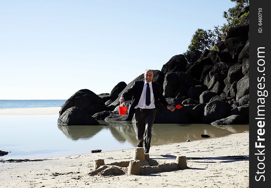 A well dressed businessman about jump on a sand castle, signifying a major business breakdown. A well dressed businessman about jump on a sand castle, signifying a major business breakdown