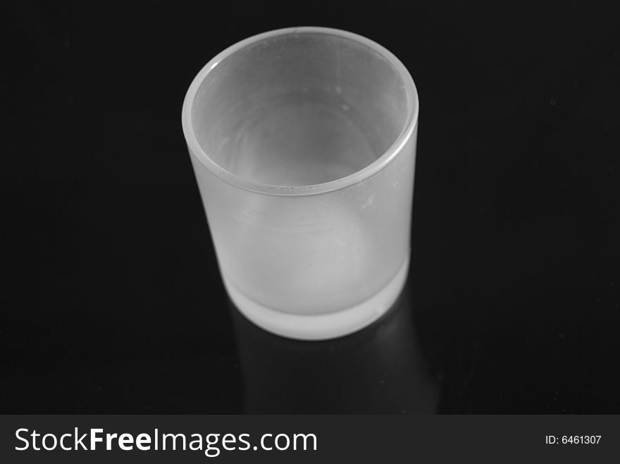 A white glass votive holder on a ultra black background. A white glass votive holder on a ultra black background